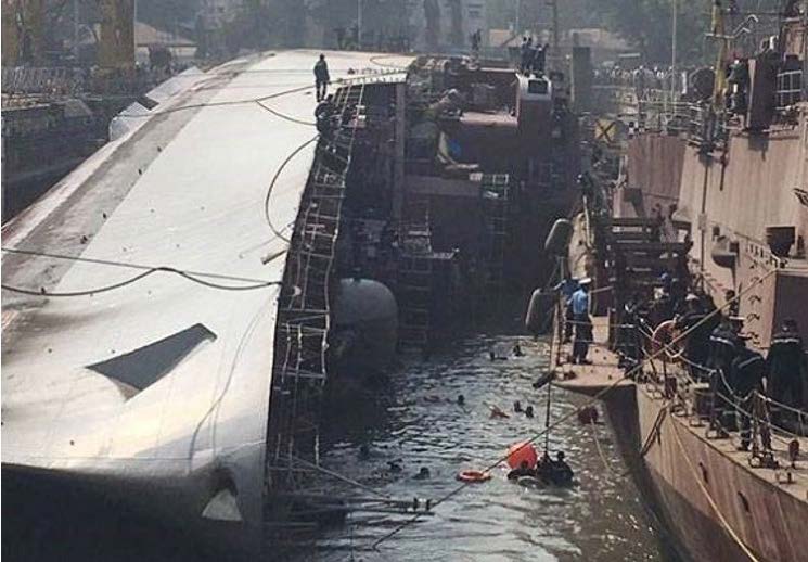 The INS Betwa on her side by a dock