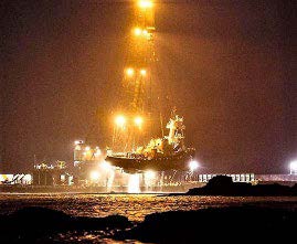A ship is hoisted above the water. This photograph was taken at night.